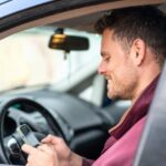 Voiture alarme : comment choisir une protection adaptée Conducteur installant une alarme dans sa voiture garée.